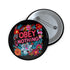 A black round pinback button featuring floral embroidery-style designs and bold red text that reads "Obey Nothing."